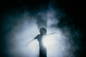 Captivating silhouette of a dancer gracefully posing amidst smoke, illuminated by dramatic backlight.